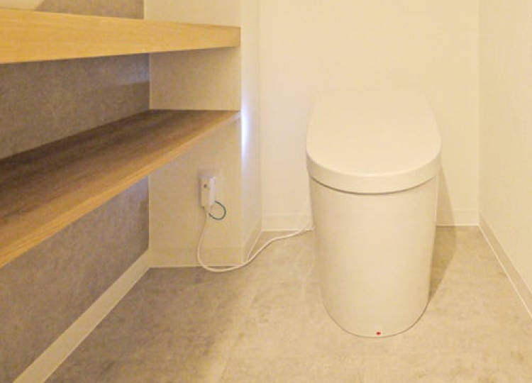 トイレットペーパーの予備などをすっきりと収納できる、奥行きの薄い棚を設置したコンパクトなトイレ空間