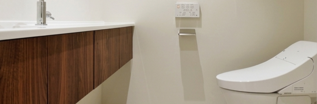 木目調の洗面台と清潔感のあるトイレ設備が設置された、モダンなリフォーム空間のイメージ