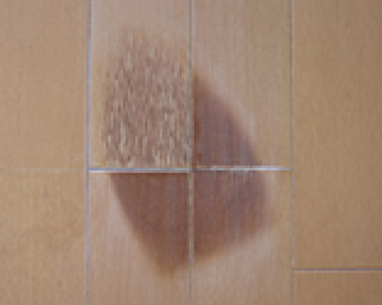 フローリングの中まで深く焦げている箇所を、木質用パテを使用してしっかりと充填している修復作業中の様子
