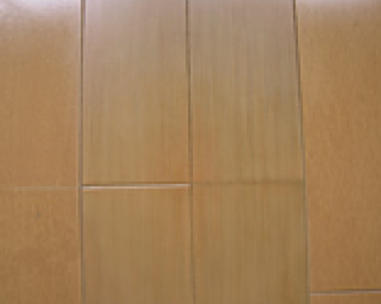 パテ埋めした変色箇所に対し、フローリングの木目に合わせて筆で丁寧に模様を描き込んでいる作業中の様子